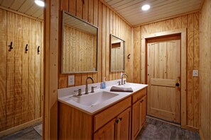 Un baño de madera con lavamanos, espejo y armarios.