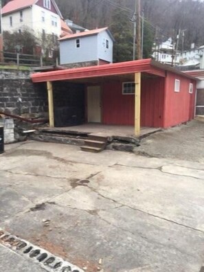 Un edificio rojo con un pequeño porche y una puerta, junto a un muro de piedra.
