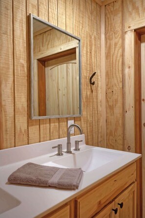 A bathroom with wooden paneling, a white sink, a mirror, and a towel.