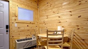 A wooden interior with a round table and chairs, a window, and a heater. - The Lodge at Welch - Both the Big and Little House (Welch)