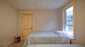 Una habitación con puerta de madera, una ventana y una cama con colcha a rayas.