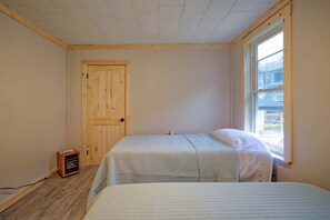 A room with a wooden door, a window, and a bed with a striped bedspread. - The Lodge at Welch (Welch)