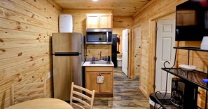 A compact kitchen with wooden walls, a refrigerator, microwave, and a sink. - The Lodge at Welch (Welch)