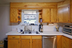 A kitchen with wooden cabinets, a stainless steel sink, a coffee maker, and a dishwasher.