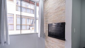 Une pièce dotée d’une grande fenêtre, d’un mur en pierre et d’un climatiseur noir.