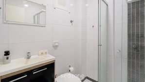 Une salle de bain moderne avec un lavabo blanc, un miroir et une douche.
