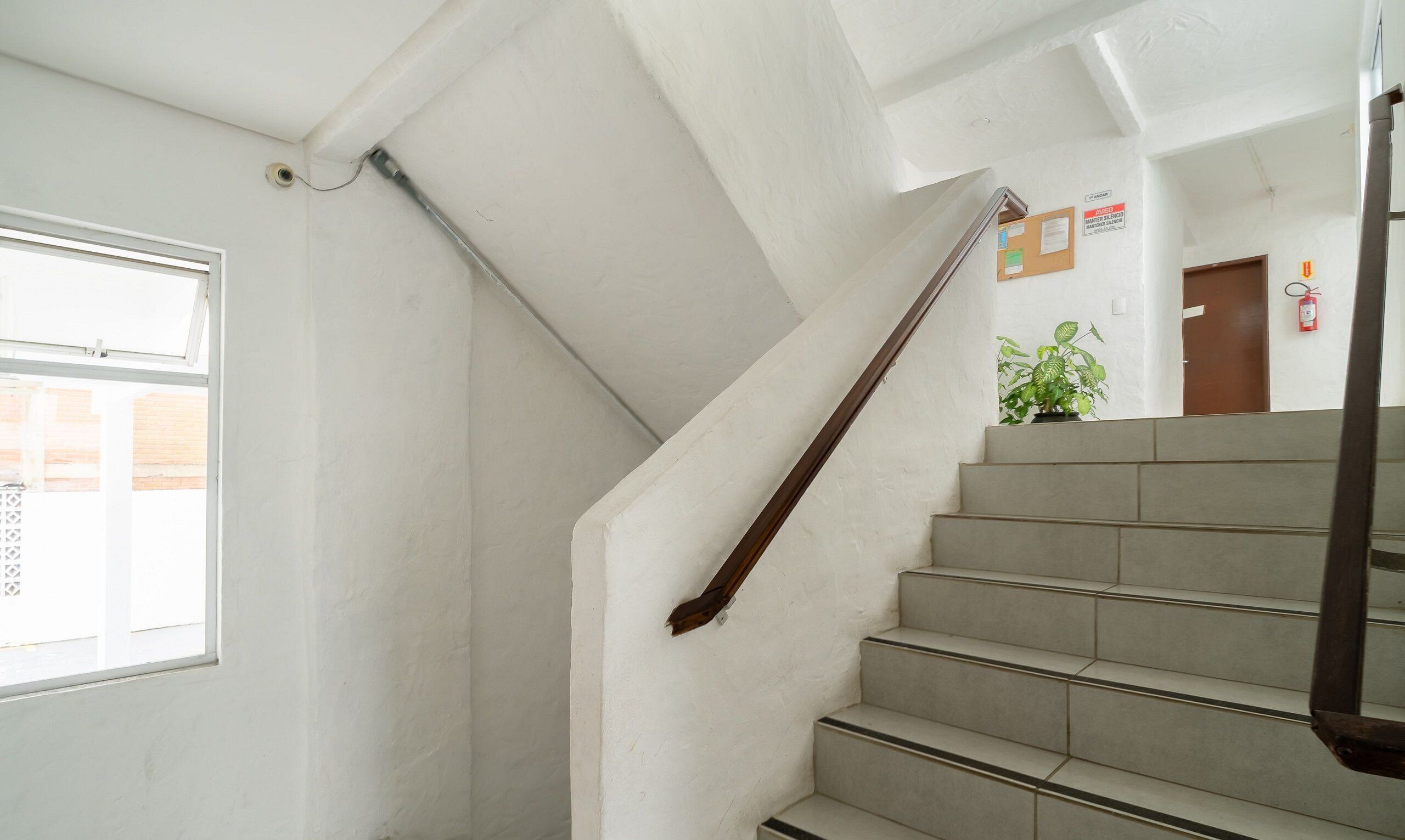 A staircase with a handrail, a window, and a door with a fire extinguisher.