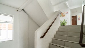 Un escalier avec une rampe, une fenêtre et une porte avec un extincteur.