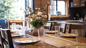 Una mesa de comedor dispuesta con platos, vasos y cubiertos, con un florero en el centro.