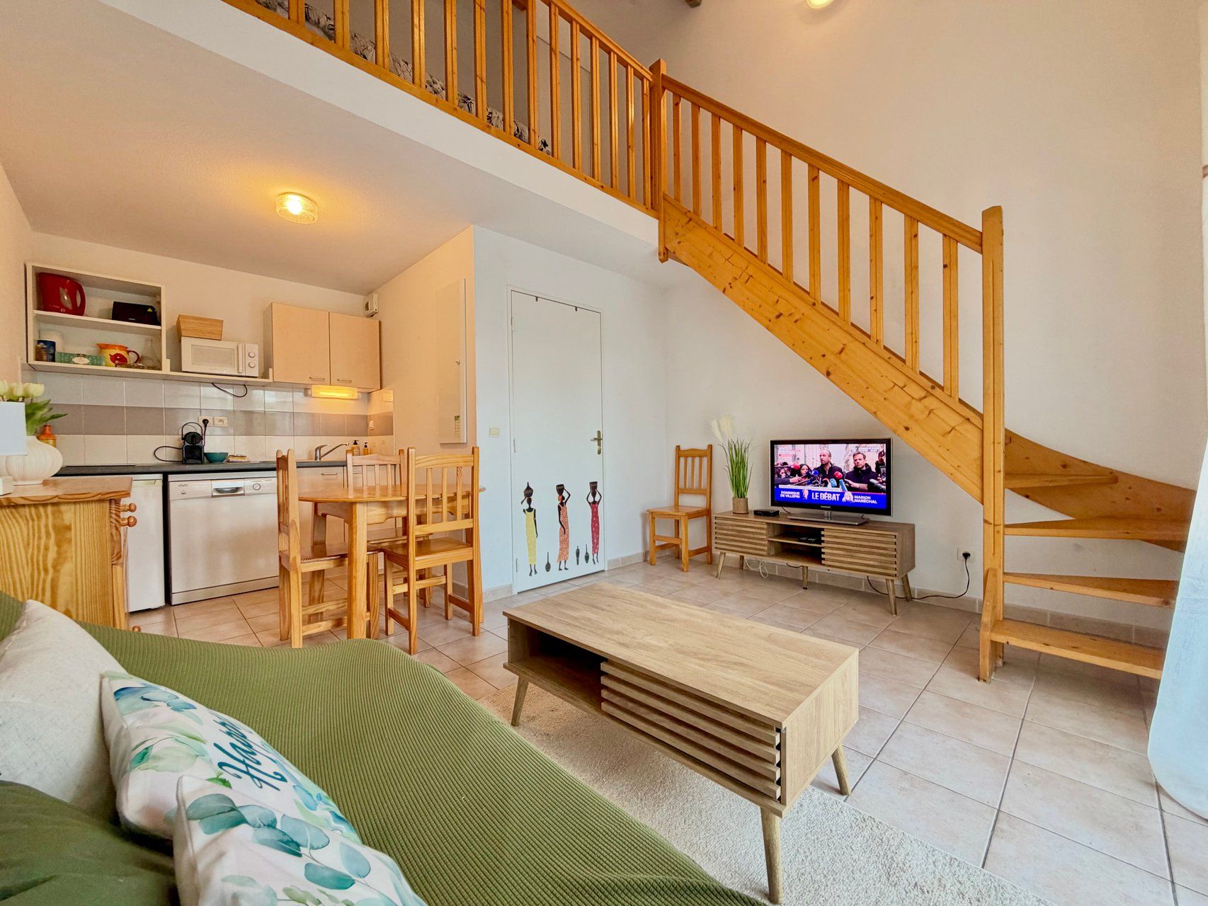 A modern apartment with a kitchen, dining area, living room, and a wooden staircase.