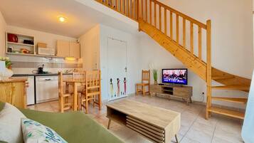 A modern apartment with a kitchen, dining area, living room, and a wooden staircase.