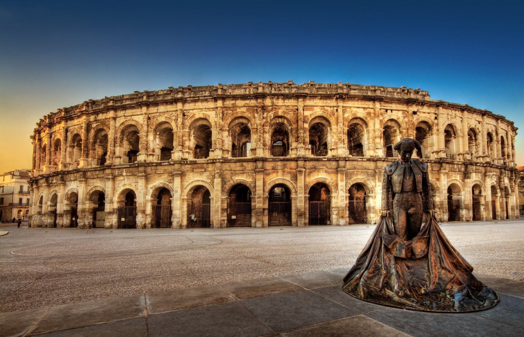 Ein historisches Gebäude mit einer kreisrunden Kolonnade und einer Statue davor.