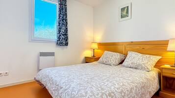 Une chambre à coucher avec un lit, des lampes de chevet, une fenêtre donnant sur un beau paysage et un luminaire au plafond.