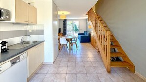 A modern kitchen with a dishwasher, microwave, and a dining area with a table and chairs. - Les Deux Terrasses, 6 guests, Pool in Calvisson (Calvisson)