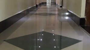 Un pasillo largo y bien iluminado con piso brillante y un gran diseño geométrico oscuro en el centro.