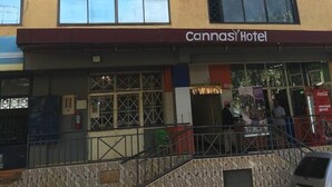 Un edificio de varios pisos con fachada amarilla y un cartel que dice "Cannasi Hotel" en la planta baja.
