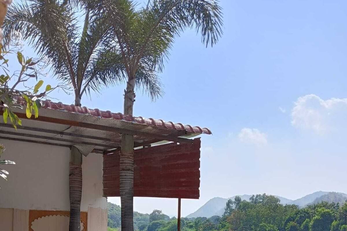 A pool area with a view of a mountainous landscape, a covered seating area, and a decorative fence.