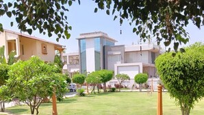 A well-maintained grassy lawn with neatly trimmed bushes and a pathway. - Udai Nature Valley Resort Udaipur (Udaipur)