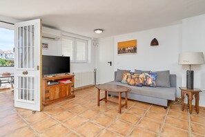 Una sala de estar con un sofá, televisor y una mesa.