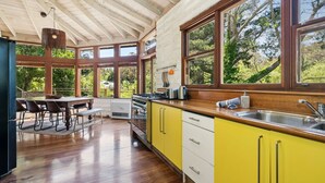 A kitchen with wooden cabinets, a large window, and a dining area with a table and chairs.