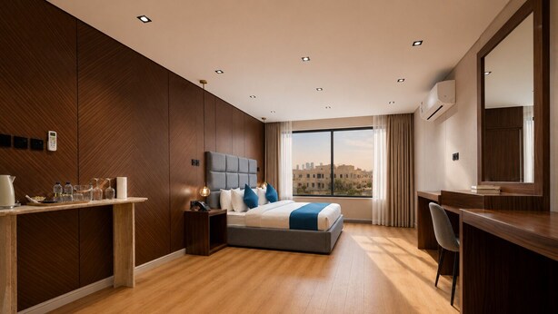 Ein modernes Hotelzimmer mit einem großen Bett, einem Schreibtisch, einem Sessel, einem großen Fenster mit Blick auf die Stadt und einer integrierten Klimaanlage.