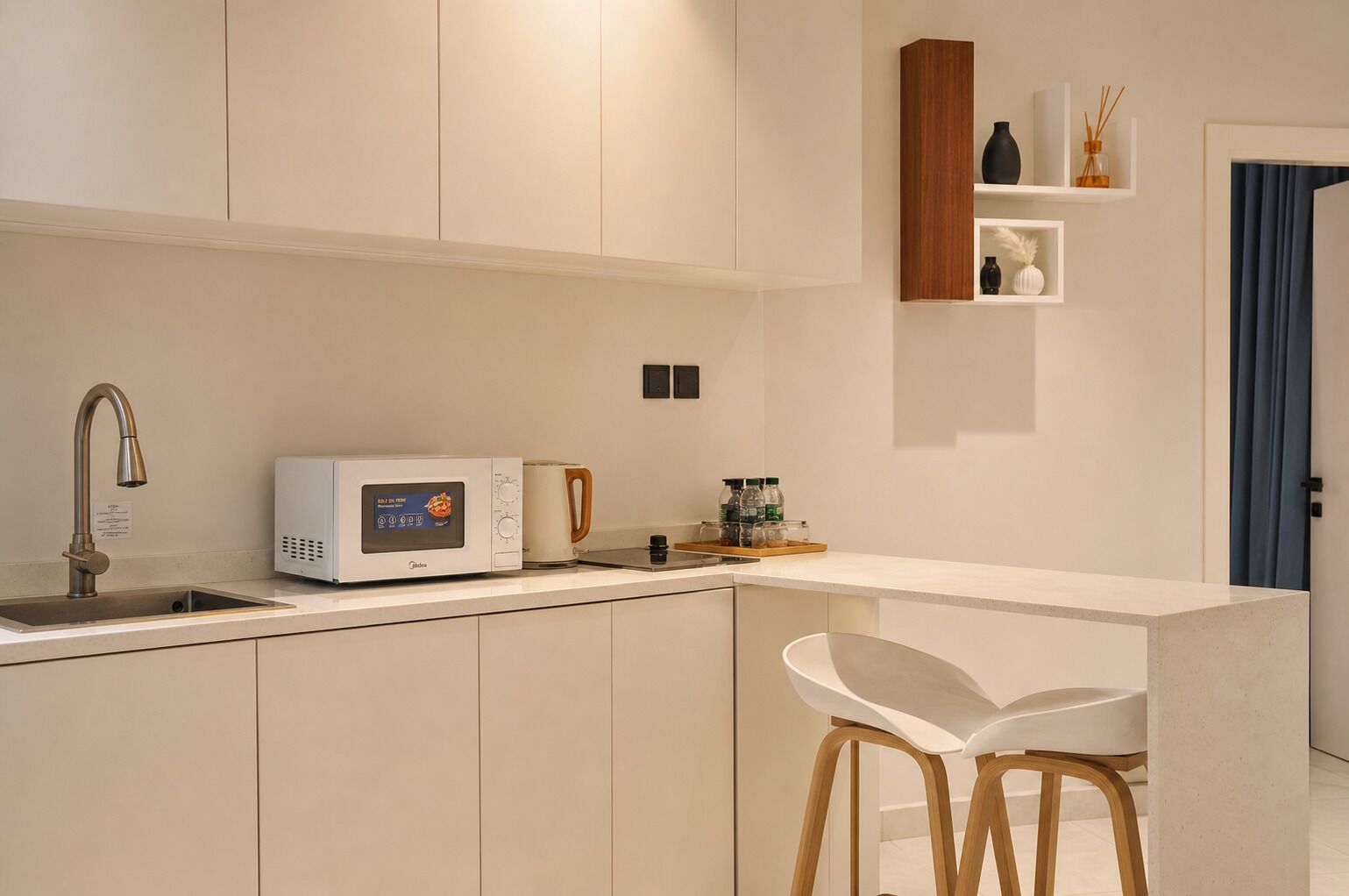 A modern kitchen with a built-in microwave, a coffee maker, and a bar area with stools.