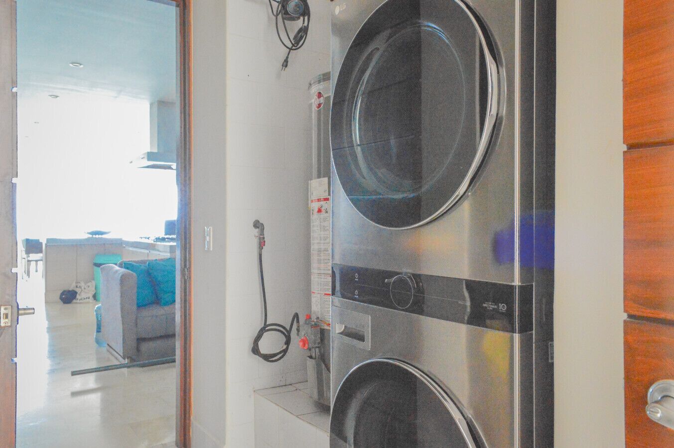 Uma lavanderia com duas máquinas de lavar empilhadas, uma mangueira e um painel de controle.