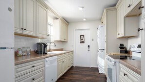 A kitchen with white cabinets, a wooden countertop, a sink, a coffee maker, and a refrigerator. - Spacious 3BR Condo w/ Private Off-Street Parking for 3 Vehicles! (Vestavia Hills)