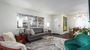 A modern living room with a grey sofa, a teal armchair, and a glass coffee table. - Spacious 3BR Condo w/ Private Off-Street Parking for 3 Vehicles! (Vestavia Hills)