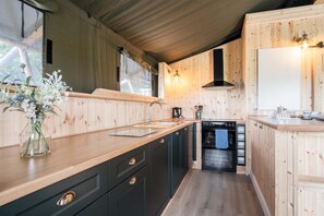 A compact kitchen with wooden walls, a sink, a stove, and a dishwasher.