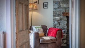 A cozy room with a brown leather armchair, a red throw blanket, and a lamp. - Rose Cottage - 3 Bedroom Cottage - Parkmill (Swansea)