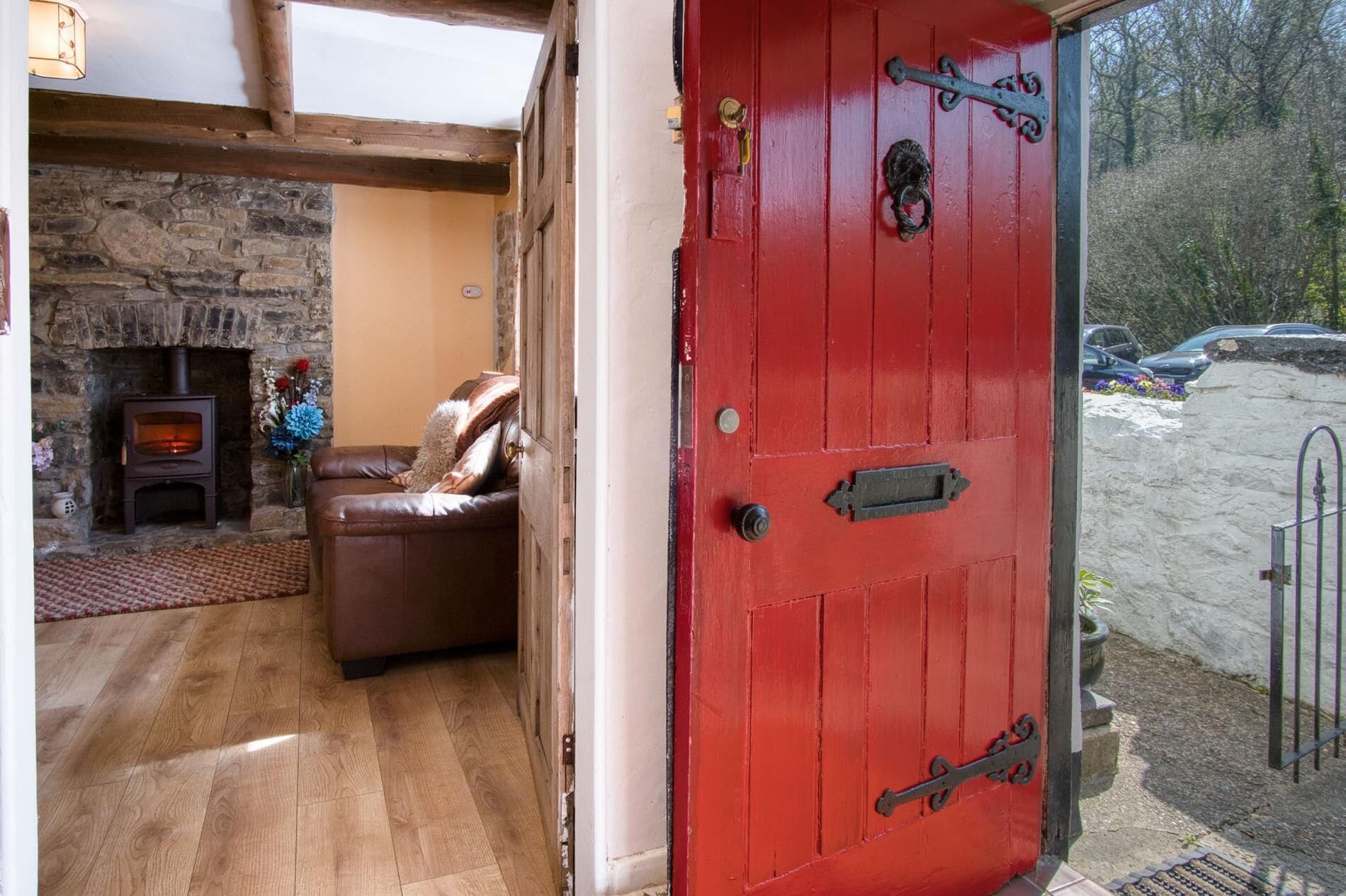 A cozy room with a stone fireplace, a red door, and a view of a parking area.