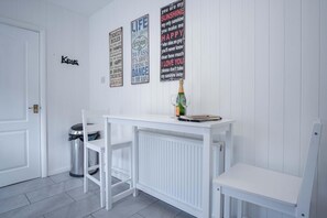 A small, white room with a white table and two chairs. There are three motivational posters on the wall. - Cefn Road - 3 Bedroom Bungalow - Glais (Swansea)