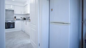 A modern kitchen with white cabinetry, a built-in oven, and a stainless steel countertop. - Cefn Road - 3 Bedroom Bungalow - Glais (Swansea)