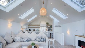 Un loft espacioso con techo alto, tragaluces, un rincón de descanso acogedor con sofá y mesa de centro, una cocina con electrodomésticos modernos y una chimenea.