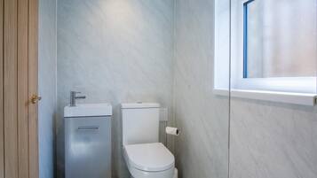 A small, modern bathroom with a toilet, sink, and window.