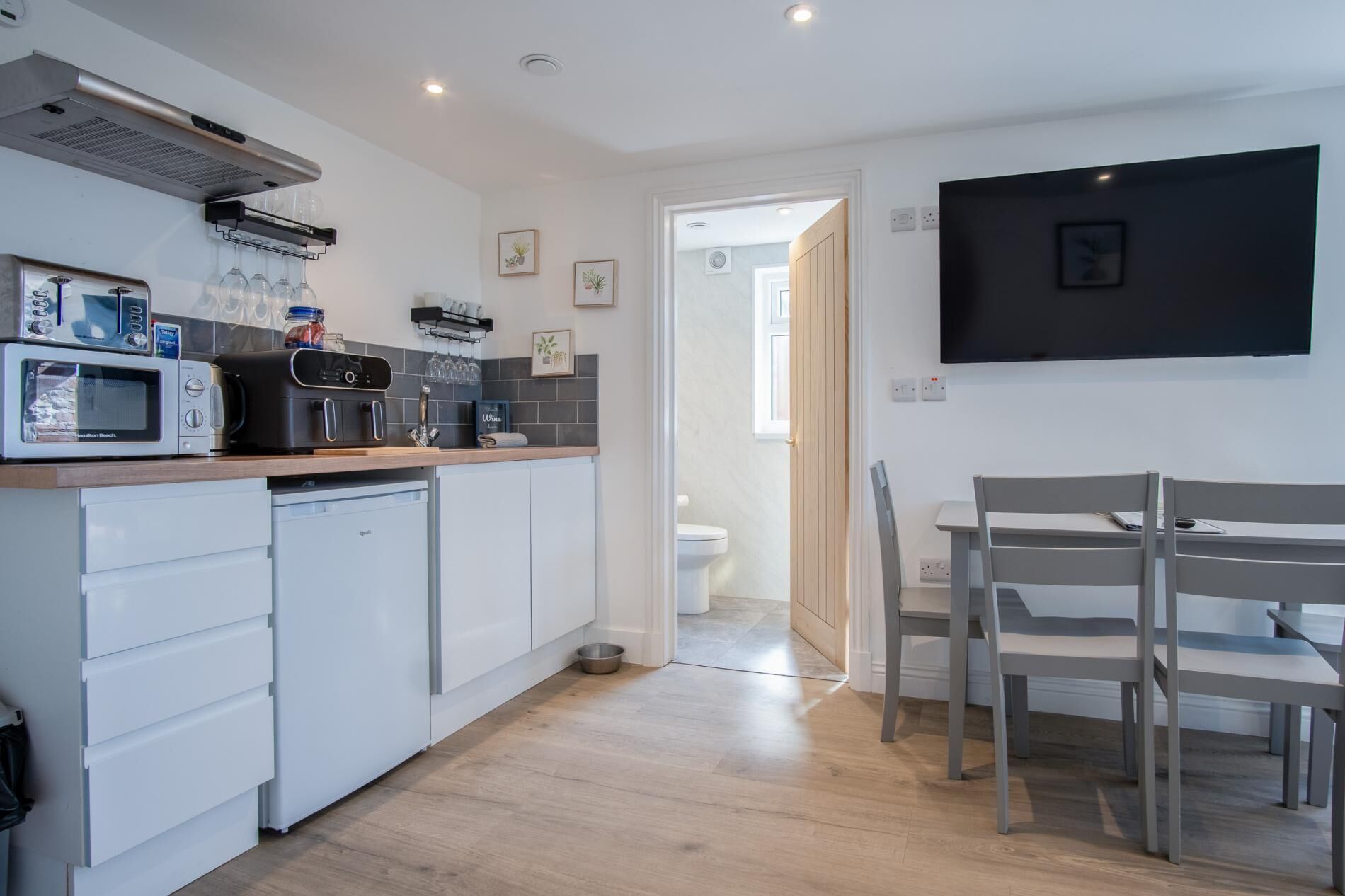 A compact kitchen with a microwave, toaster, and coffee maker. There is a dining area with a table and chairs.
