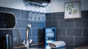 Una cocina moderna con un lavamanos de acero inoxidable, un soporte para copas de vino y un letrero que dice 'Time to Wine down'.