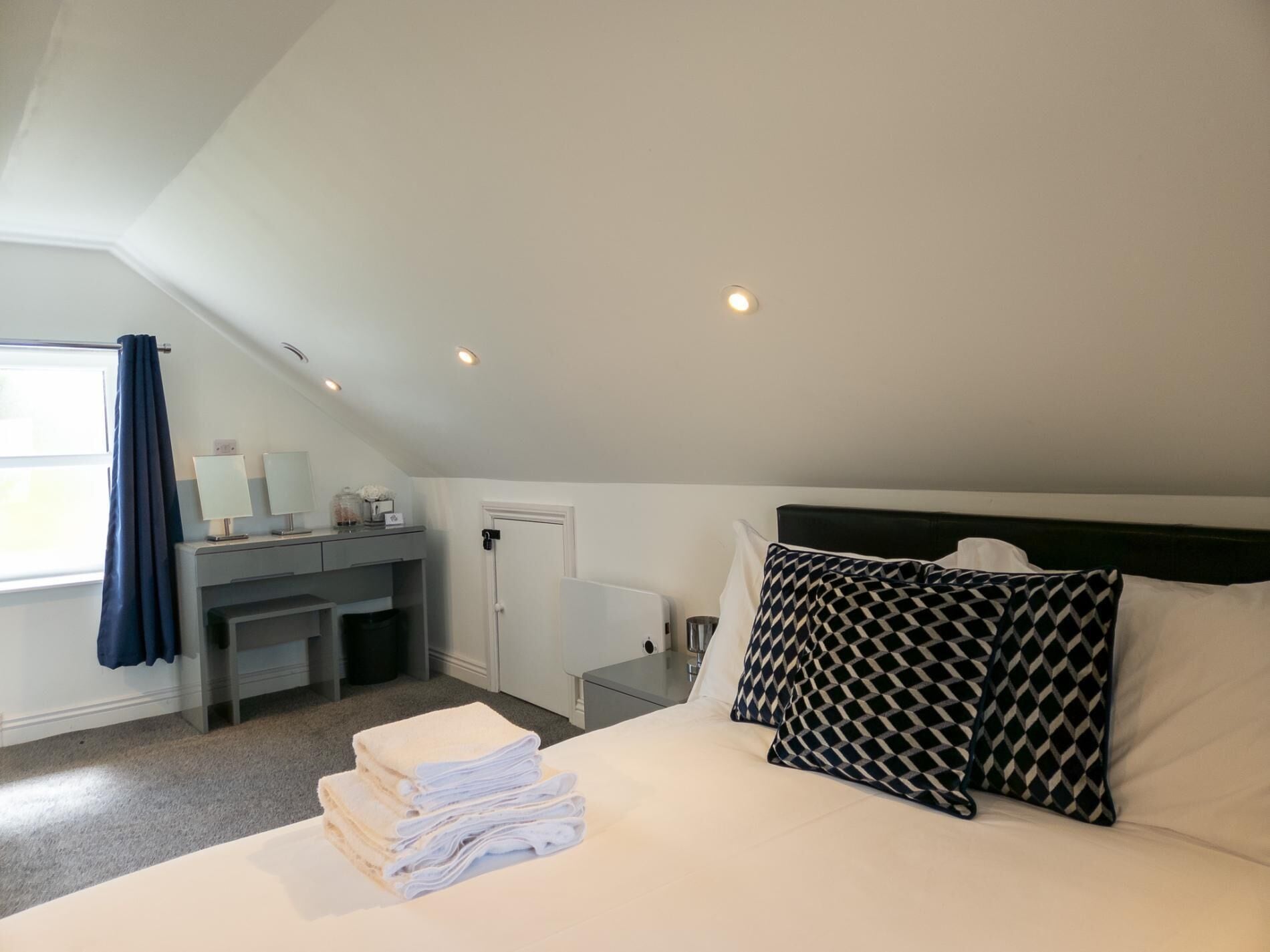 Una habitación de hotel con cama, escritorio y ventana con cortinas.