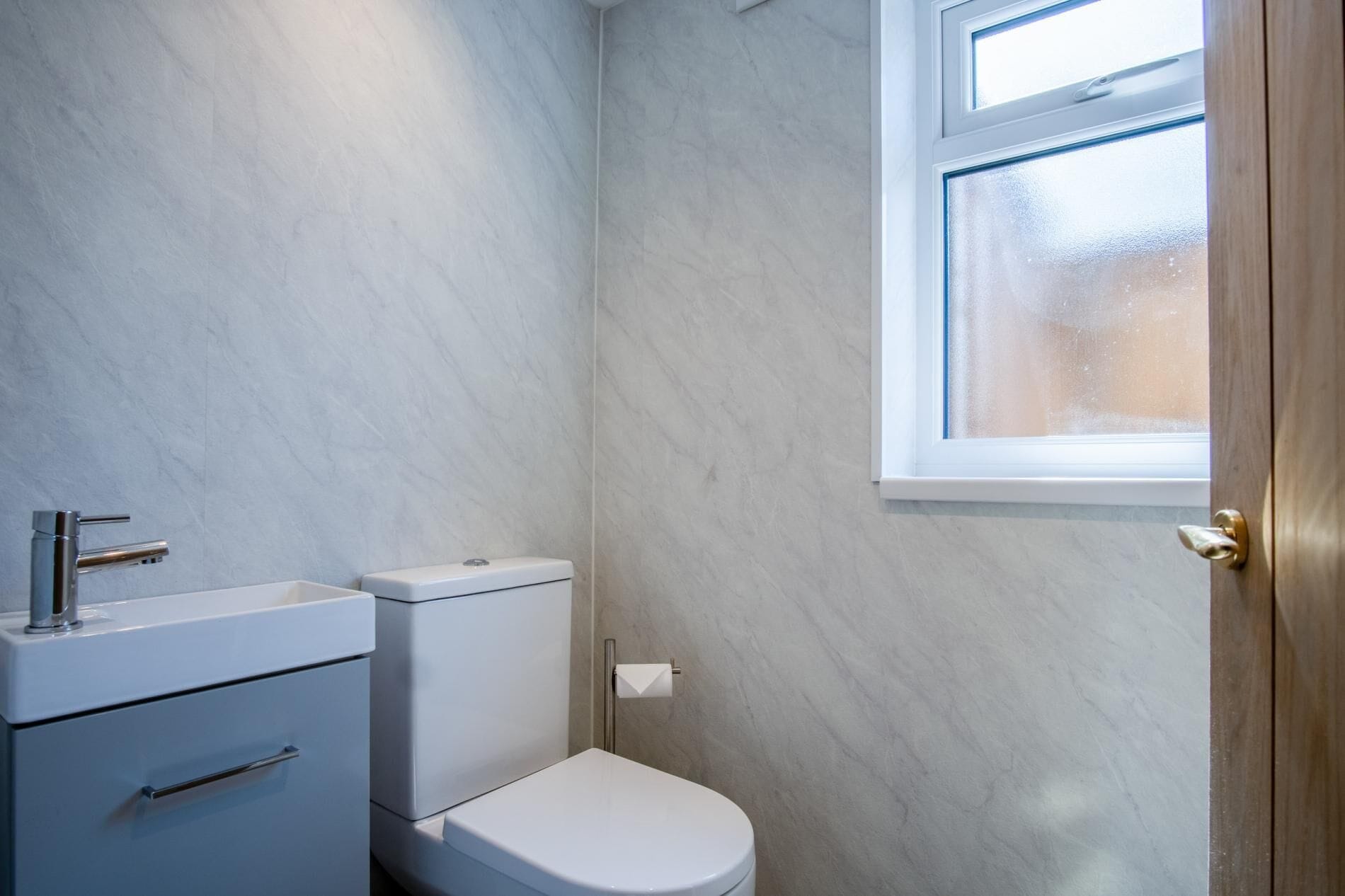 Un baño con inodoro, lavamanos y ventana.