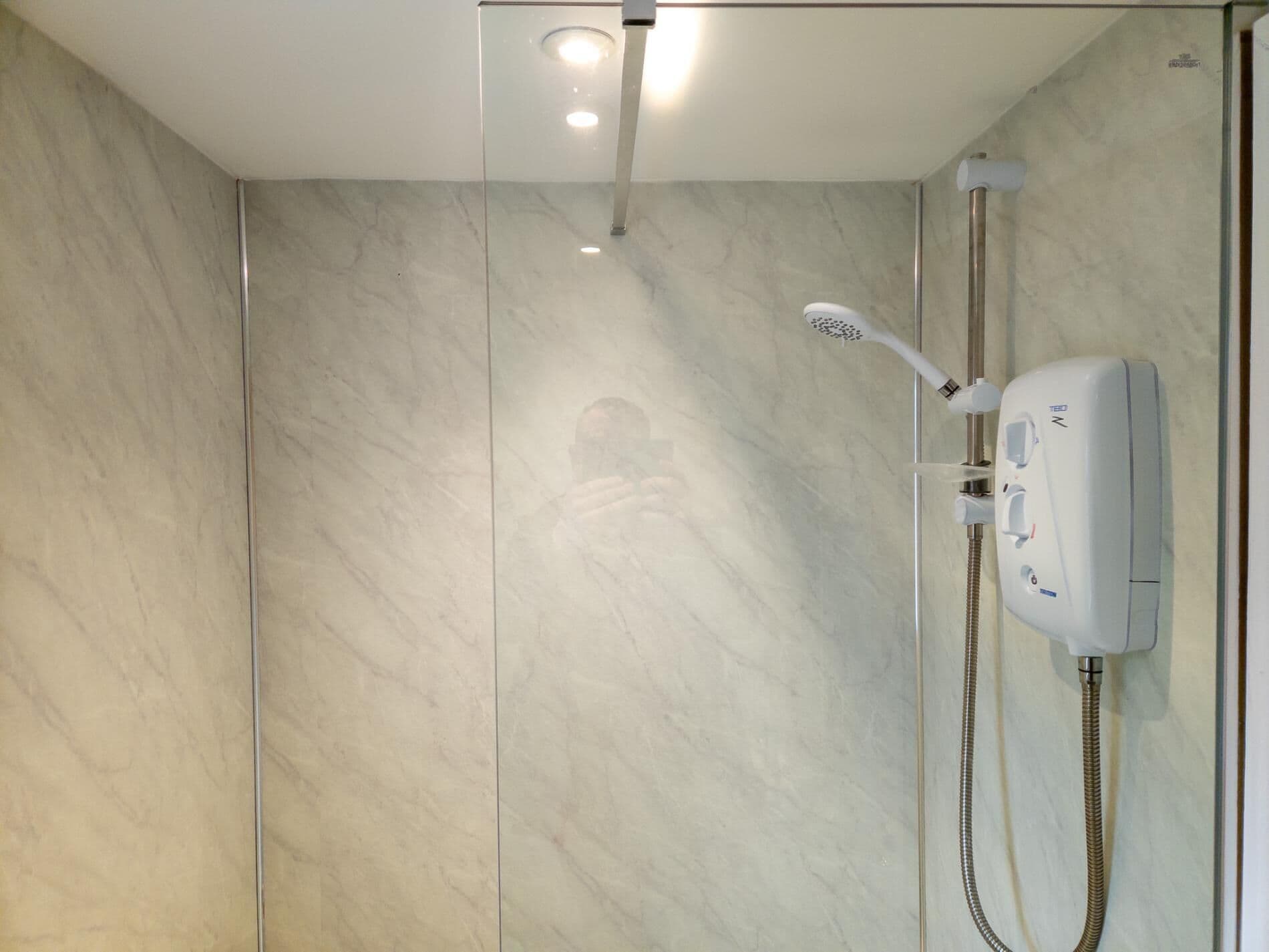 Un bagno moderno con cabina doccia in vetro, soffione a mano e rubinetto a parete.