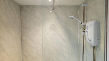 Un bagno moderno con cabina doccia in vetro, soffione a mano e rubinetto a parete.