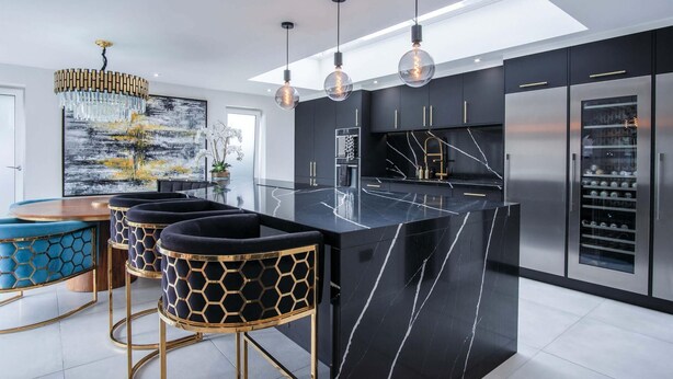 A modern kitchen with a black marble island, stainless steel appliances, and a large window.