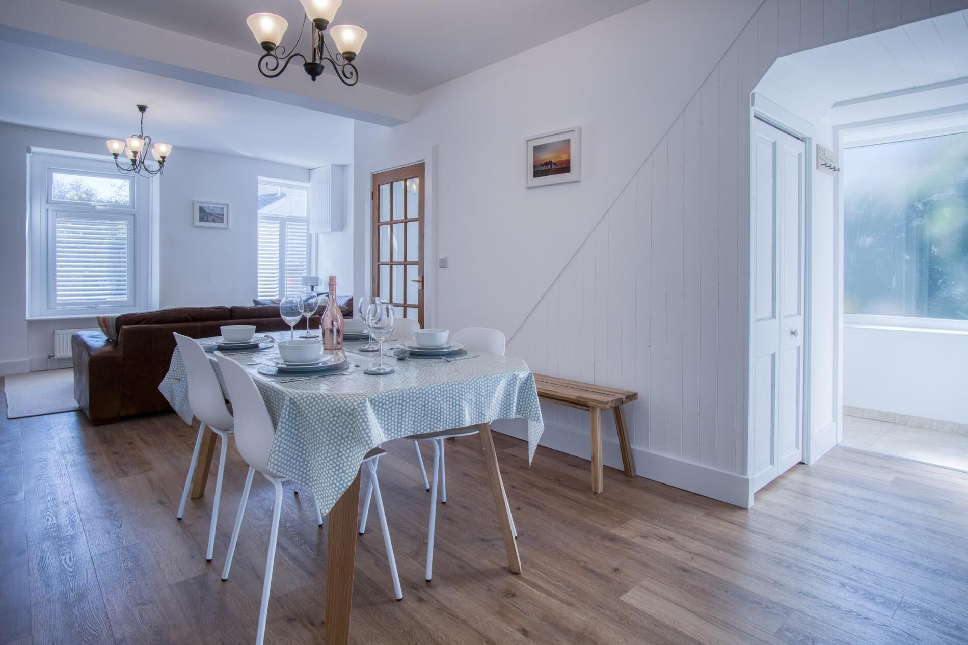 Un coin repas avec une table dressée pour quatre personnes, un canapé marron et un lustre.