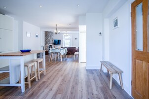 Una cocina amplia con comedor, piso de madera y una pared de acento de piedra.