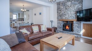 Una sala de estar con chimenea de piedra, sofá de cuero y mesa de centro de madera.