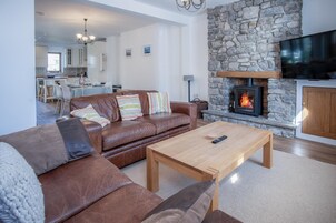Una sala de estar con chimenea de piedra, sofá de cuero y mesa de centro de madera.