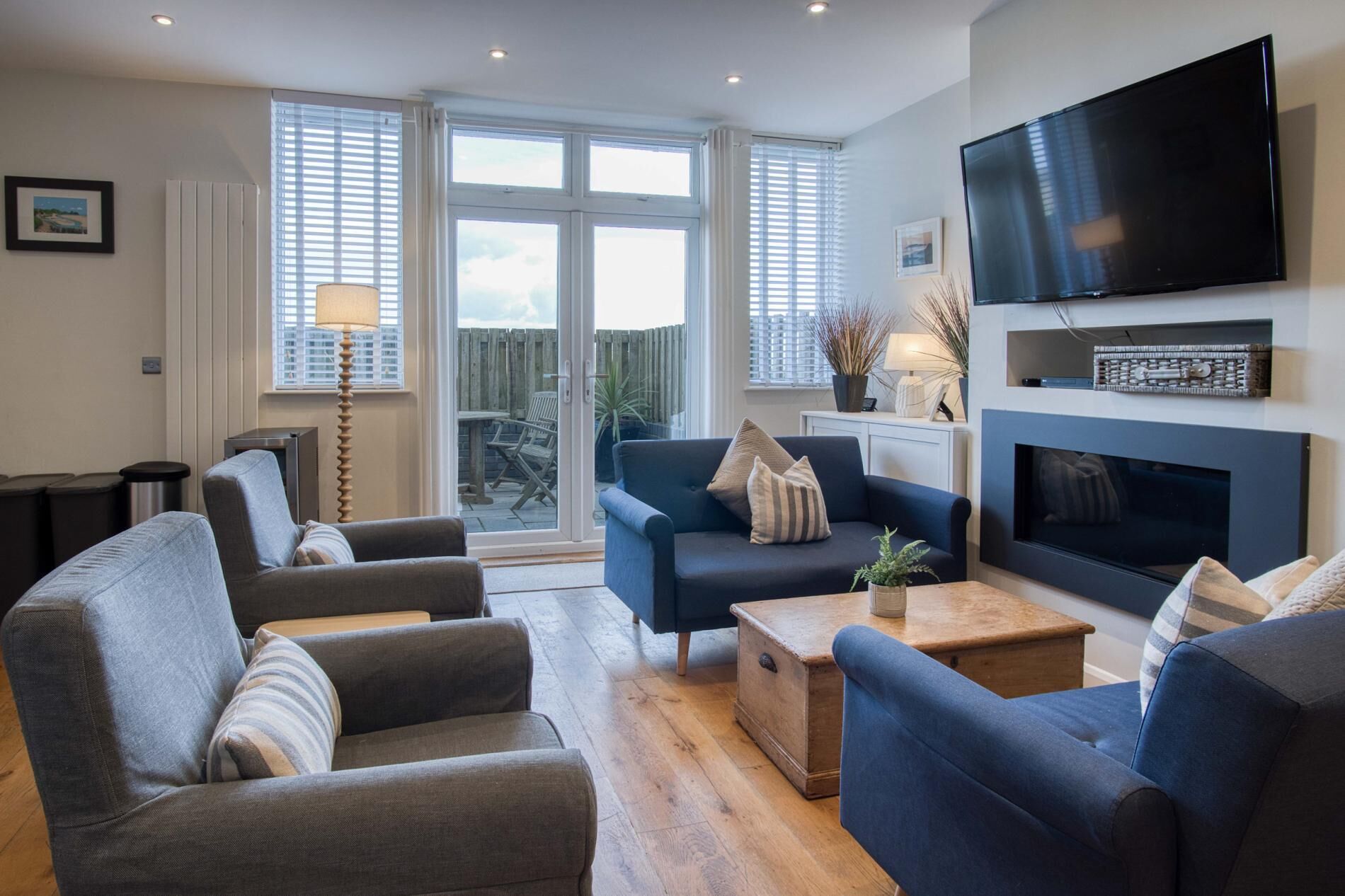 A modern living room with a fireplace, comfortable seating, and a large TV.