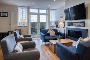 Una sala de estar moderna con chimenea, asientos cómodos y un televisor grande.