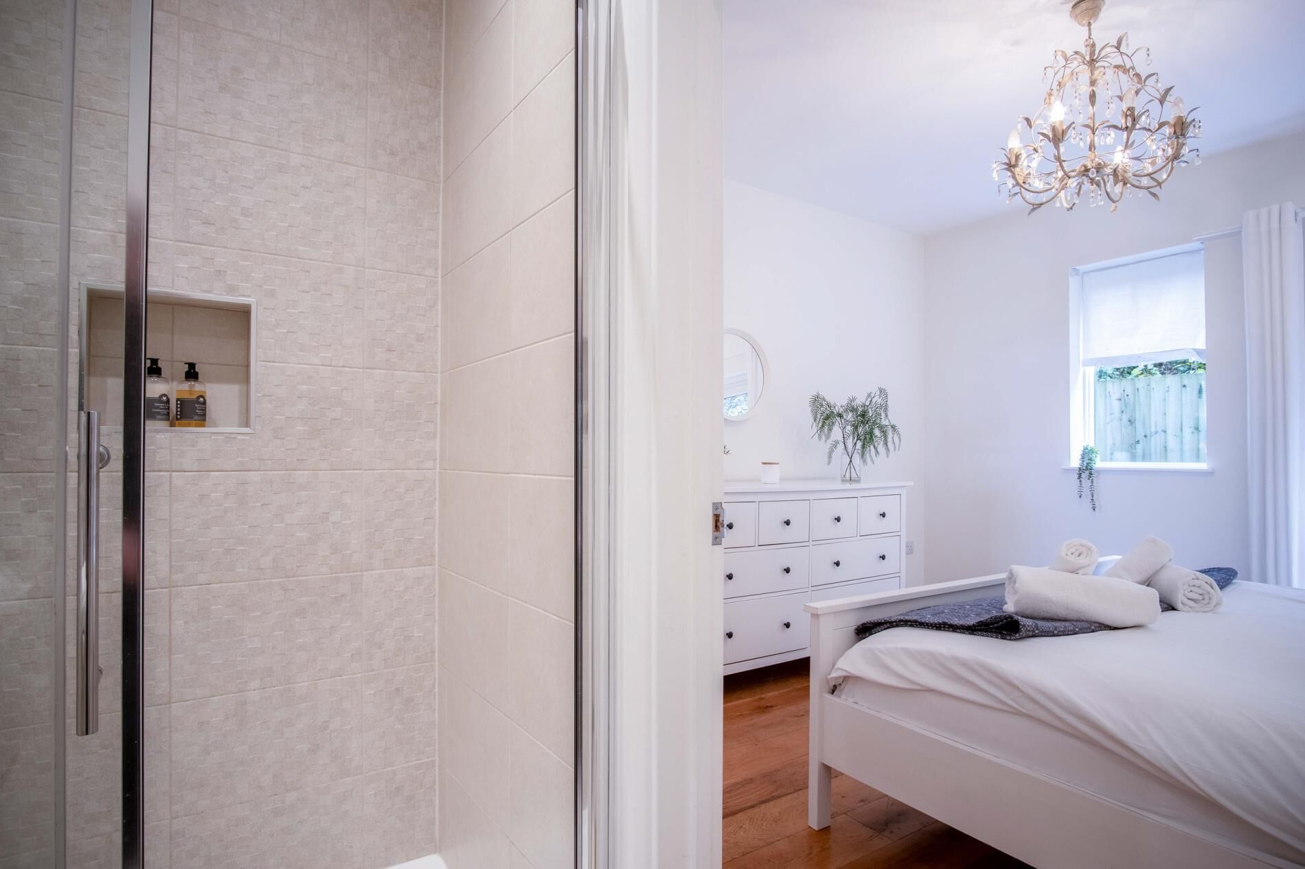 Een slaapkamer met een bed, nachtkastje, dressoir en een raam met uitzicht.